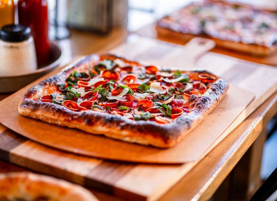 A square pizza on a wooden serving board